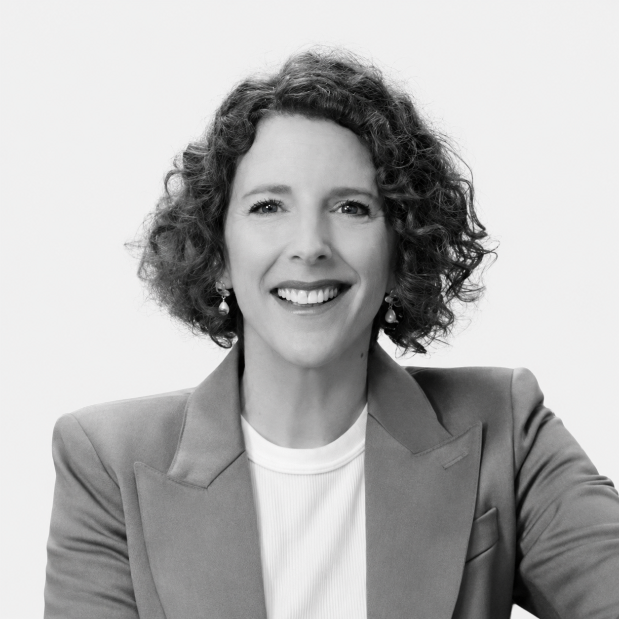 Black-and-white headshot of Chrissy Sturt, smiling and wearing a blazer.