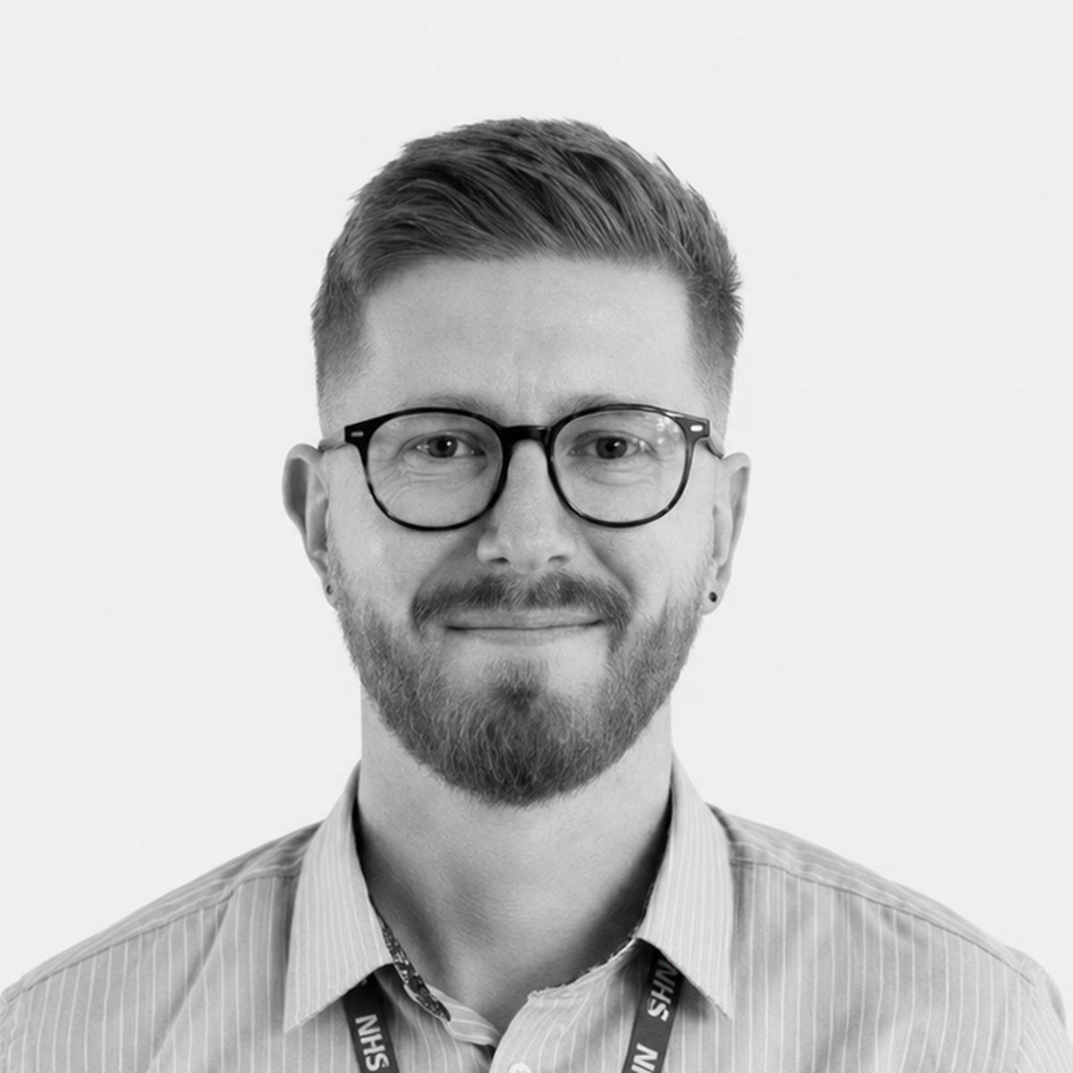 Black-and-white headshot of Mike Dahl, wearing glasses, a striped shirt and an NHS lanyard.