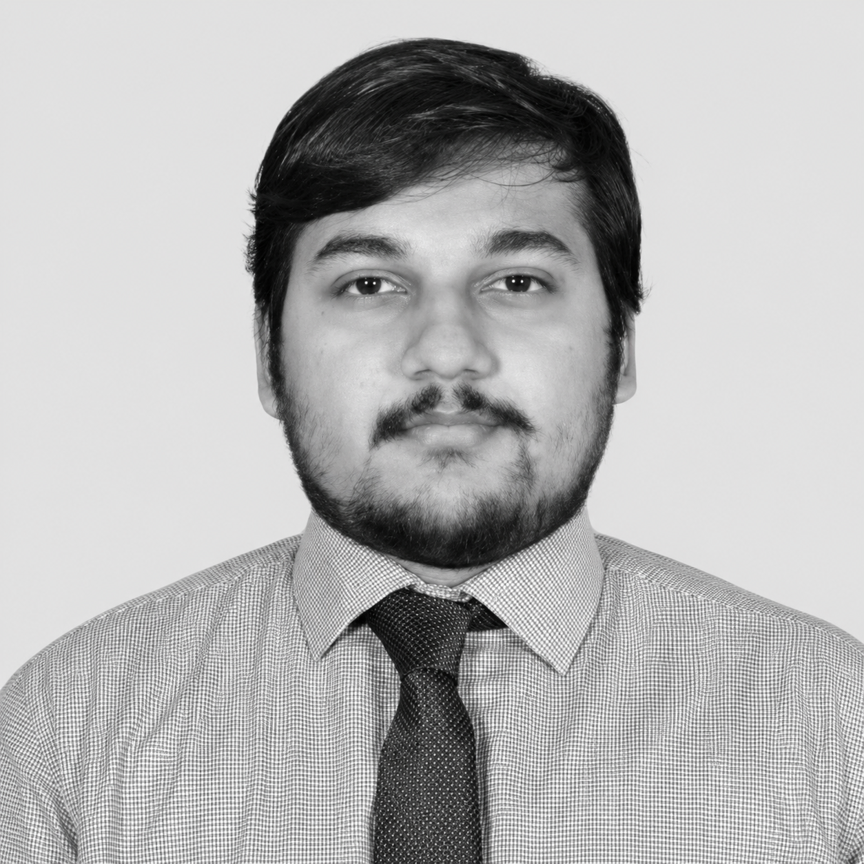 Black-and-white headshot of Shrayan Banerjee, wearing a shirt and tie and looking at the camera.